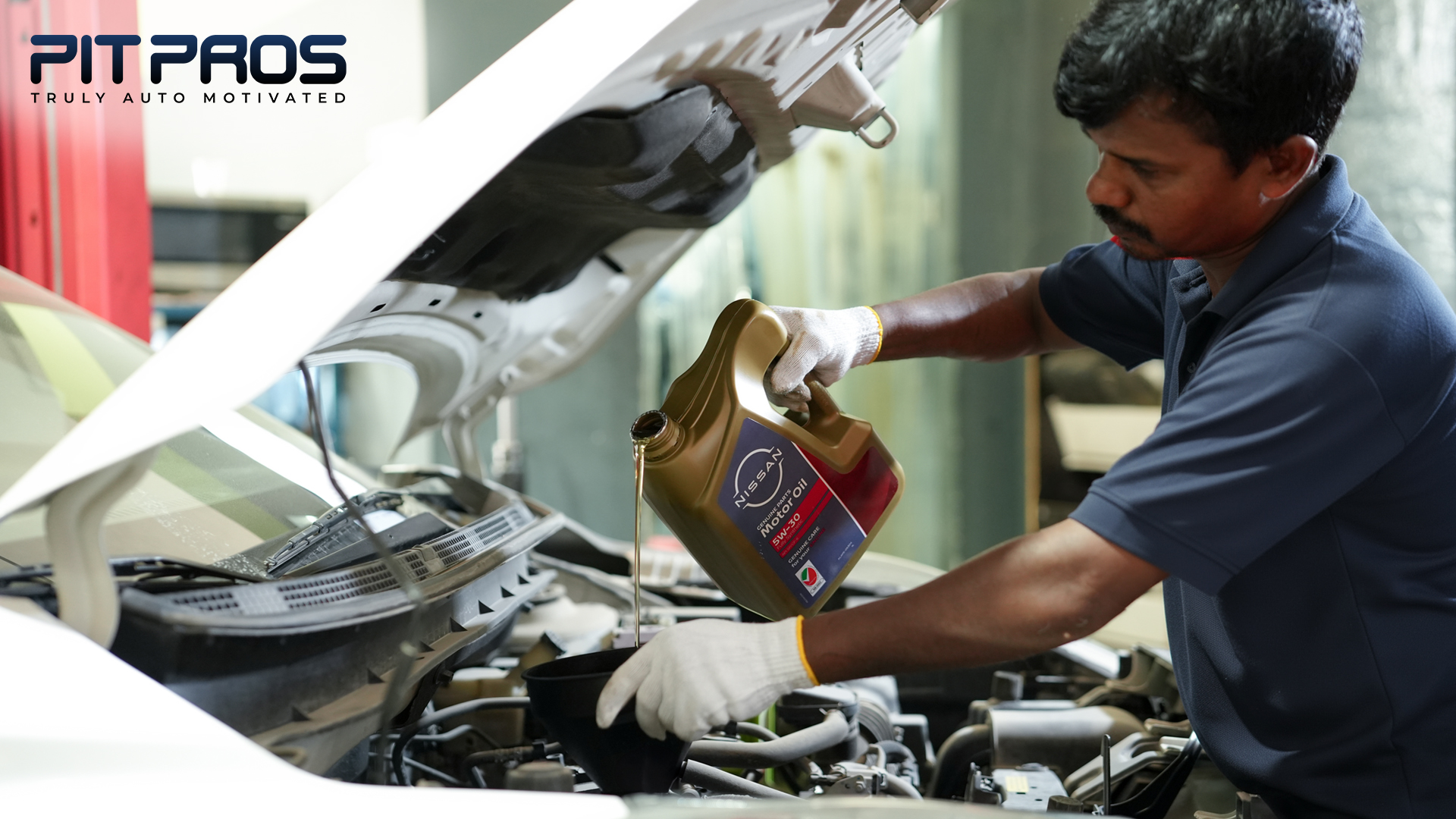 Technician performing an engine oil change using Nissan synthetic motor oil at PitPros car service center in Dubai Investment Park 2.