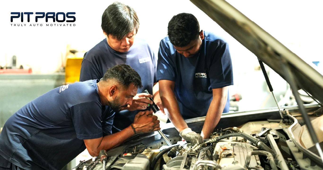 “Three automotive technicians working together inside a workshop, inspecting and repairing a car engine at Pit Pros.”